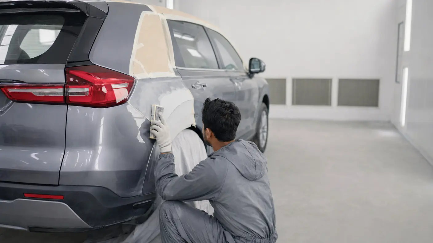Technician preparing a repaired rear quarter panel on an unbadged compact crossover before paint refinishing.