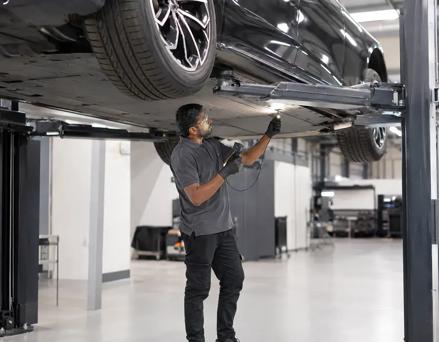 Underbody Contact Needs a Deliberate View Technician inspecting Mercedes-Benz EQS underbody contact near protective covers and EV boundaries